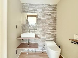 a bathroom with a white toilet and a stone wall at The Lobs Brand New, 4 bedroom, 3 bath, 4 toilet, 8 min to Rusutsu, 7-11, bus at door in Kimobetsu