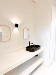 a bathroom with a black sink and two mirrors at Le FauBourg Suites in Antwerp