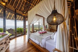 a bedroom with a bed and a chandelier at Ketanu Bamboo Lodge Sumba in Praikalogu
