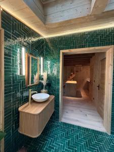 a bathroom with a sink and green tiles at Ecolodge de la Palombiere in Saint-Clar