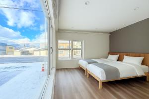 two beds in a bedroom with a large window at The Lobs Five, Brand New, 4 bedroom, 3 bath, 4 toilet, 8 min to Rusutsu, 7-11, bus at door in Kimobetsu