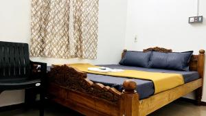 een slaapkamer met een houten bed en een stoel bij Le Beach Villa, Luxurious Stay Opposite Auroville Beach, ECR Road in Kuilapayam