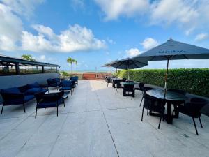 a patio with tables and chairs and an umbrella at Unity - Flat Premium à Beira-Mar em Cabo Branco in João Pessoa