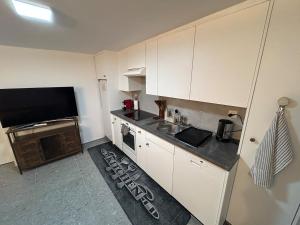 a small kitchen with white cabinets and a tv at Gemütliche Souterrainwohnung mit gratis Parkplatz in St. Gallen