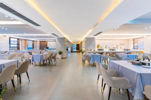 a dining room with white tables and chairs at Tiancheng Hotel Liangjiahe Metro Station Branch in Kunming