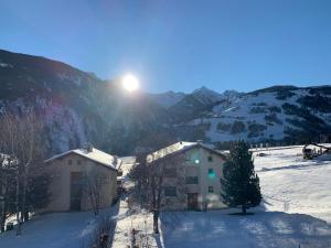 a building in the snow with the sun in the background at Casa Caglina in Disentis