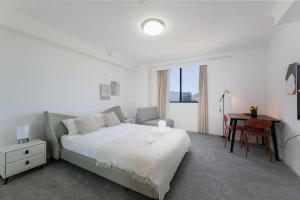 ein weißes Schlafzimmer mit einem Bett und einem Tisch in der Unterkunft The Arcadia in CBD w Parking Desk Gym Pool in Sydney