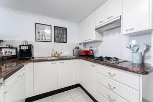 eine weiße Küche mit weißen Schränken und einem Herd in der Unterkunft The Arcadia in CBD w Parking Desk Gym Pool in Sydney