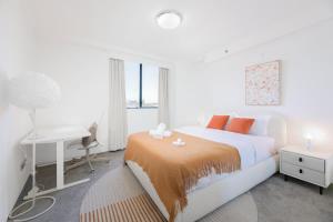 ein weißes Schlafzimmer mit einem Bett und einem Schreibtisch in der Unterkunft The Arcadia in CBD w Parking Desk Gym Pool in Sydney