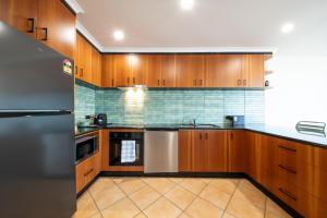 eine Küche mit Holzschränken und einem Edelstahlkühlschrank in der Unterkunft Bella Isola in Airlie Beach