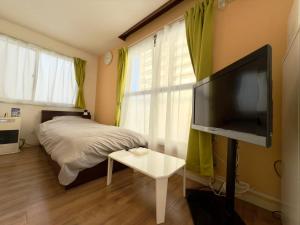 a bedroom with a bed and a flat screen tv at 2-6大通駅まで地下鉄で4駅の場所で美室のリフォーム済みアパートメント in Sapporo