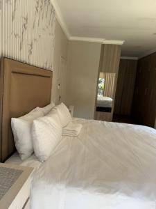 a bedroom with a large bed with white pillows at Bee Boutique Lodge in Nelspruit