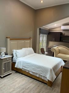 a bedroom with a bed and a table and a chair at Bee Boutique Lodge in Nelspruit