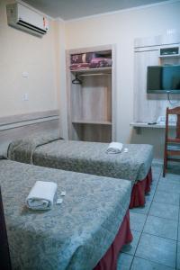 a hotel room with two beds and a television at Colonial Hotel in Campo Grande