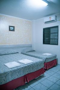 two beds in a hotel room with towels on them at Colonial Hotel in Campo Grande +24 photos