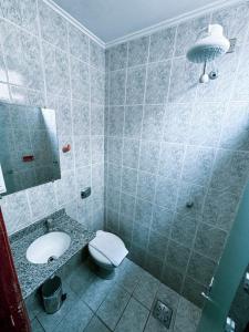 a bathroom with a toilet and a sink and a mirror at Colonial Hotel in Campo Grande