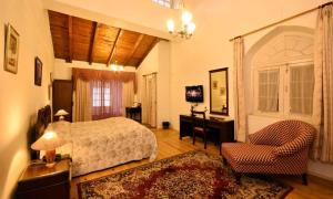 a bedroom with a bed and a chair and a desk at Belvedere Palace Nainital in Nainital +2 photos