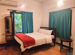 PūrnānkuppamCeleste Luxury Bungalow的一间卧室，配有一张带绿色窗帘的床和一扇窗户 更多13张照片