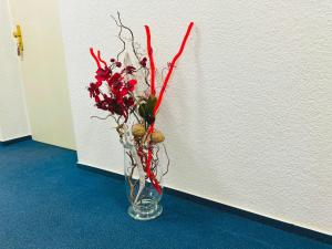 a glass vase with red flowers in it on the floor at Hotel an der Rennbahn in Dresden