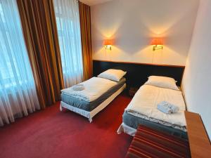 two beds in a hotel room with windows at Hotel an der Rennbahn in Dresden