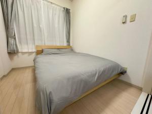 a small bed in a room with a window at 401好立地札幌駅徒歩7分と大通駅徒歩6分で都心を満喫で綺麗な部屋で快適が生活が実現 in Sapporo