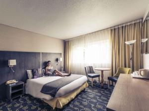 a woman sitting on a bed in a hotel room at Mercure Annecy Sud in Annecy +57 photos