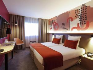 a hotel room with a large bed and a desk at Mercure Lyon Charbonnières in Charbonnières-les-Bains +135 photos