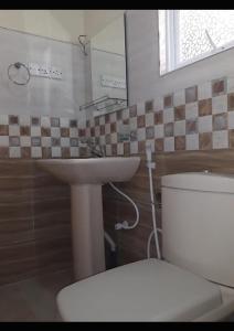 Un baño con lavabo, inodoro y espejo. en NK Hotel & Resturaunt, en Matale 4 fotos más