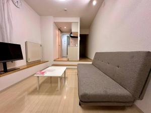 a living room with a couch and a table at 410札幌駅徒歩7分と大通駅徒歩6分で好立地な都心を満喫でき綺麗な部屋で快適が生活が実現 in Sapporo