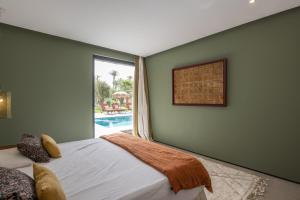 a bedroom with a bed and a window and a pool at Modern villa - 4 luxury suites - Golf Amelkis - Marrakech in Marrakech +40 photos