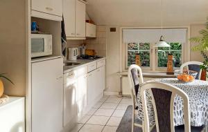 eine Küche mit einem Tisch mit Stühlen und einer Mikrowelle in der Unterkunft Cozy Home In Ermelo With Wifi in Tonsel