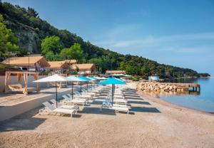 a group of chairs and umbrellas on a beach at Valamar Camping Lanterna - Adriacamps in Poreč