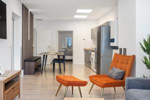 a living room with orange chairs and a kitchen at City Apartment in Uelzen