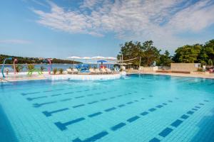 a large blue swimming pool with chairs and umbrellas at Valamar Camping Lanterna - Adriacamps in Poreč +8 photos