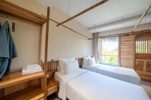 a bedroom with two beds and a window at Vanlong garden in Kon Rung (1)