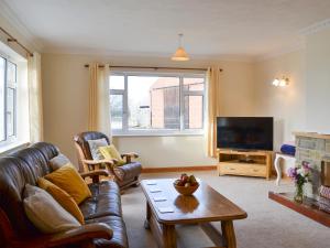a living room with a leather couch and a television at Ivy Grange Cottage in Wistow