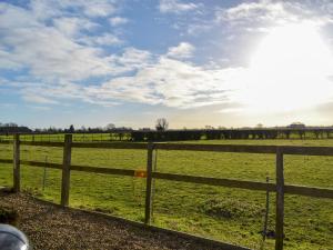 a fence in front of a green field at Ivy Grange Cottage in Wistow