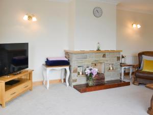 a living room with a stone fireplace and a couch at Ivy Grange Cottage in Wistow