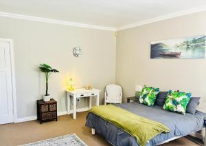 a bedroom with a bed and a table with a chair at Little Oasis - Palm Room in Port Elizabeth