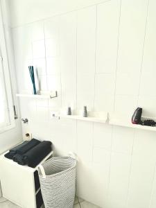 a white tiled bathroom with a bench and a basket at White Home Forli Centro in Forlì +6 photos