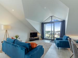 a living room with two blue couches and a tv at Scilla - Uk50179 in Helston