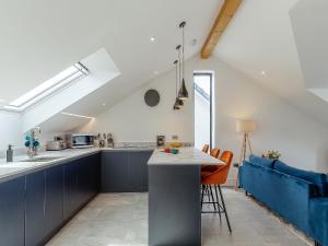 een zolderkeuken met blauwe kasten en een blauwe bank bij Scilla - Uk50179 in Helston