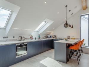 een keuken met blauwe kasten en een aanrecht met oranje stoelen bij Scilla - Uk50179 in Helston +25 foto's