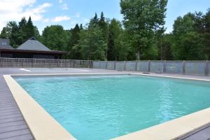 a swimming pool in a backyard with a fence at Hôtel Lodge du Lac Chambon in Murol