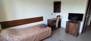 a bedroom with a bed and a flat screen tv at Dom Studencki Zbyszko in Poznań