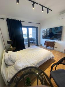 a bedroom with a large white bed and a tv at Mango in Madinaty