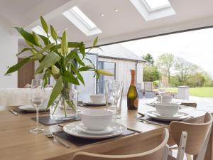 a dining room table with a bottle of wine and a plant at Manor Lodge Stables in Wiston