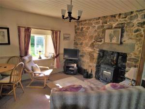 a living room with a stone fireplace and a tv at Tigh Na Maraiche in Isle of Jura
