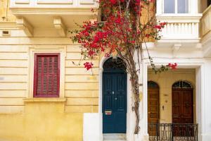 Ensuite twin room at quiet and friendly townhouse في سليمة: مبنى ذو باب أزرق ونوافذ حمراء