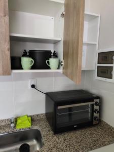 圣地亚哥-德尔埃斯特罗Departamento Centrico Santiago piso 1 Y 2的厨房台面上放着一台微波炉和两个绿色碗。 更多19张照片